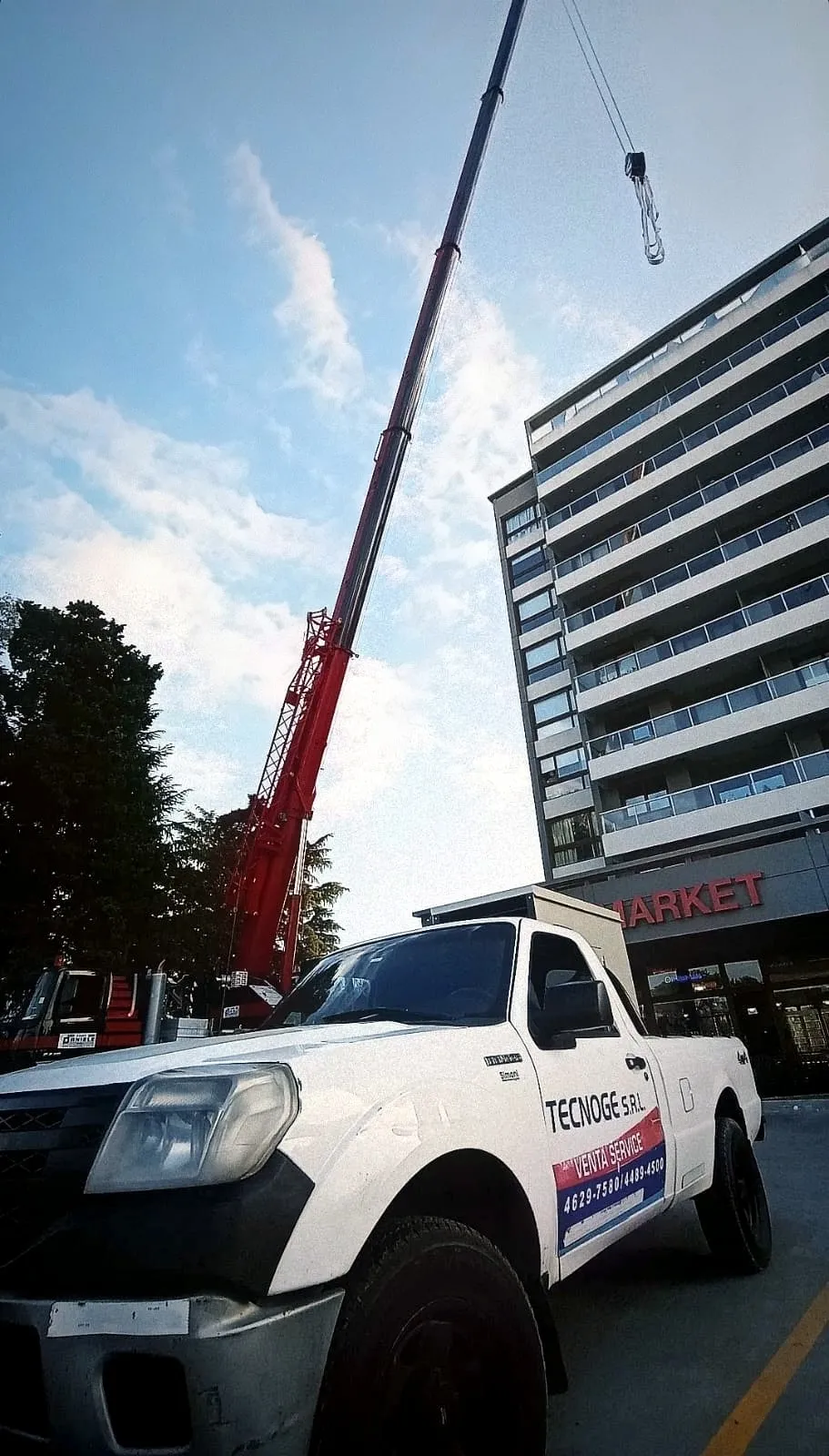 Izaje de un grupo electrógeno con grúa frente a un edificio