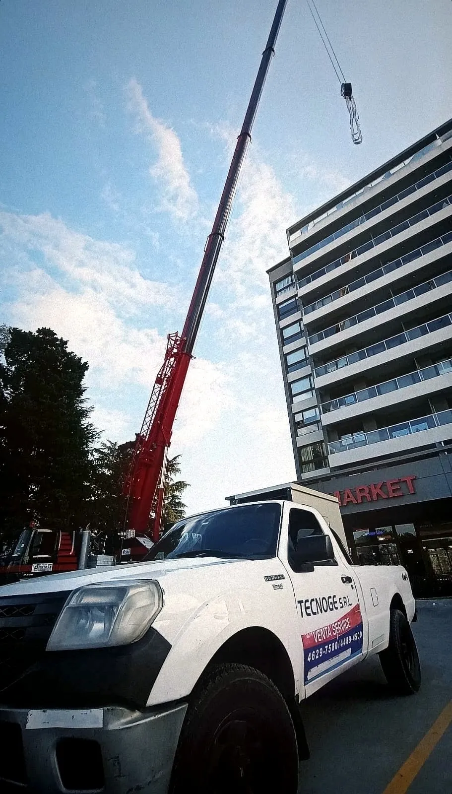 Izaje de un grupo electrógeno con grúa frente a un edificio